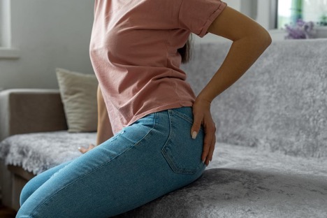 A woman holding her buttocks with her left hand due to her hemorrhoid pain.
